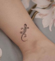 a small gecko tattoo on the left ankle and right leg, with flowers in the background