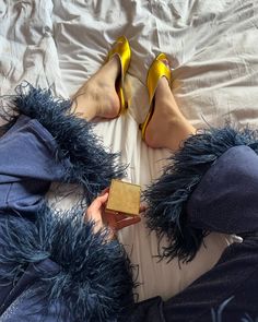 a woman laying on top of a bed wearing high heels and holding a golden block