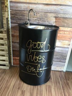 a black bucket with gold lettering on it sitting in front of a wooden paneled wall