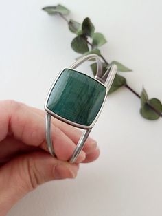 This large square Larsonite* is a deep sea-green color with darker greens sweeping across its surface. Simply set atop a cuff bracelet, the curving lines of silver give this statement cuff an elegant, feminine style. On the underside of the stone, waves of silver are cut away to reveal the beautiful underside of this unique stone. Elegant Feminine Style, Flying Crow, Sea Green Color, Green Jasper, Square Stone, Elegant Feminine, Sea Green, Deep Sea, Feminine Style