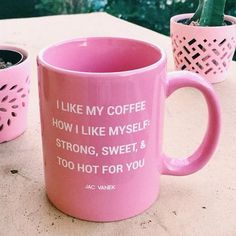 two pink coffee mugs sitting on top of a table next to each other with words written on them