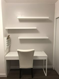 there is a white desk and chair in the room with shelves on the wall behind it