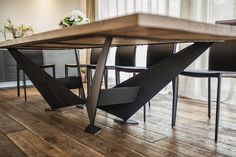 a wooden table with black chairs and white flowers on the top is surrounded by wood flooring