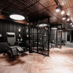 an office with wooden floors and black walls is lit by spotlights from the ceiling