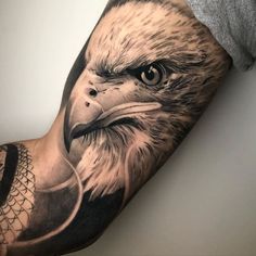 an eagle tattoo on the arm with a bird in it's beak and head