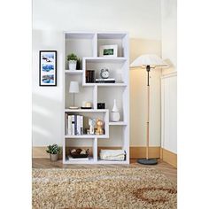 a white book shelf with books and other items on top of it in a living room