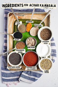 the ingredients for achar ka masala laid out in bowls on a tray with spoons