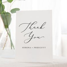 a thank you card sitting on top of a table next to a vase filled with flowers