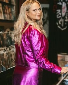 a blonde woman in a purple dress is looking at the cd's on display