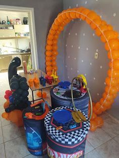 an orange balloon arch is in the middle of a room with other balloons and decorations