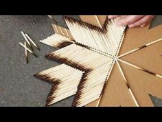 two hands are working on an ornament made out of matches and wood sticks