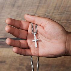 a person holding a cross in their hand on a wooden table with a chain attached to it