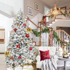 a living room with a christmas tree in the corner and other decorations on the stairs