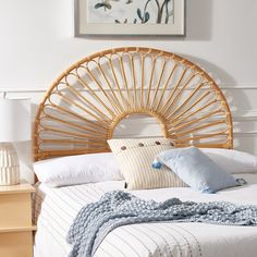 a bed with white linens and blue pillows in a room that has a bamboo headboard