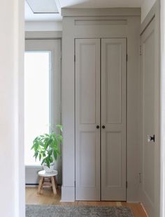 an empty room with two doors and a plant in the corner