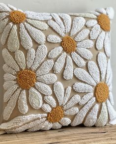 a white and yellow pillow sitting on top of a wooden table