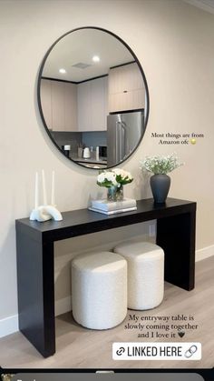 a black table with two stools and a round mirror on the wall above it