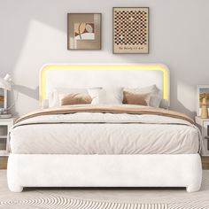 a white bed sitting in a bedroom next to two pictures on the wall above it