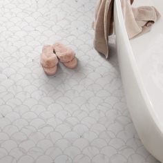 a pair of slippers sitting on the floor next to a bathtub