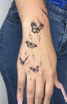 a woman's hand with three butterflies on it and stars in the sky above her