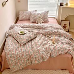 a teddy bear sitting on top of a bed next to pillows and blankets in a bedroom