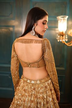 Ombre gold and silver bridal lehenga embellished with sequin, crystals, beads, cutdana embroidery, and a matching full-sleeved blouse in gold. The lehenga comes with a shaded embroidered cutwork dupatta.DELIVERY TIMEPlease allow 8-12 weeks for your outfit to arrive.FABRIC DETAILSNetProfessional cleaning only. Golden Lehenga Blouse Designs, Festive Designer Hand Embellished Choli, Festive Semi-stitched Hand Embellished Choli, Glamorous Gold Sets With Intricate Embroidery, Festive Hand Embellished Semi-stitched Choli, Gold Saree Dress With Mirror Work, Glamorous Gold Sharara With Mirror Work, Glamorous Lehenga With Unstitched Blouse, Bollywood Style Hand Embellished Blouse Piece For Reception