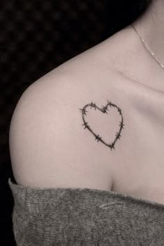 a heart shaped barbed wire tattoo on the upper half of a woman's chest