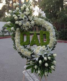 a floral wreath with the word dad written in green letters and white flowers on it