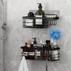 two black shelves with bottles and soaps on them in the corner of a bathroom