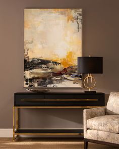 an abstract painting hangs on the wall next to a chair and table with a lamp