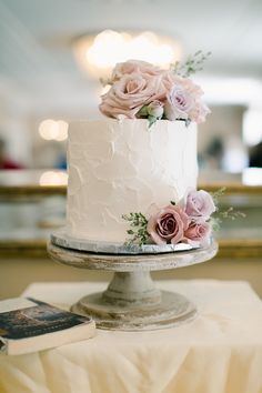 there is a white cake with flowers on the top and bottom, sitting on a table