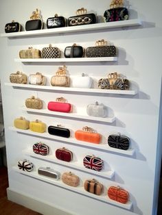 a white wall filled with lots of different types of clutches and purses on shelves