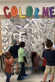 children are standing in front of a wall with the word color me painted on it