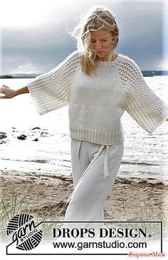 a woman standing on top of a sandy beach next to the ocean with her arms outstretched