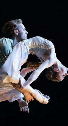 two people are performing on stage in the air with their arms around each other,