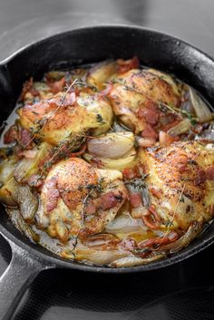 a skillet filled with chicken and onions on top of a stove