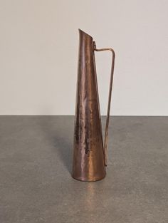 a metal pitcher sitting on top of a gray counter next to a white wall and floor