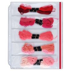 four different colors of yarn on display in a clear plastic case with red, pink, and black handles