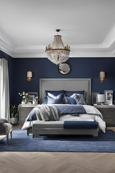 a bedroom with blue walls and white bedding in the center, along with a chandelier