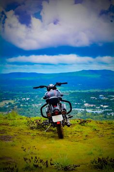 a motorcycle parked on top of a lush green hillside