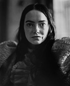 a black and white photo of a woman with an owl on her shoulder, looking at the camera