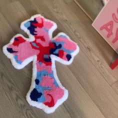 a pink and blue cross shaped rug sitting on top of a wooden floor