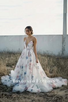 a woman in a dress standing in the middle of a field with her back to the camera