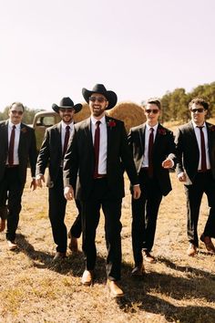 a group of men in suits and ties walking across a field