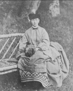 an old black and white photo of a woman sitting on a bench with a blanket over her head