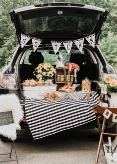 the trunk of a car is filled with food and decorations for an outdoor wedding reception