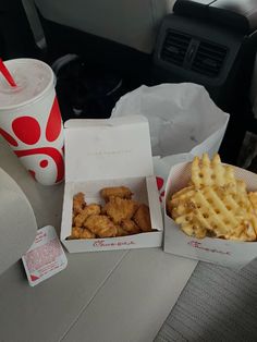 two boxes of chicken and waffles next to a cup of drink on a table