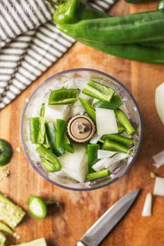 an overhead view of a food processor filled with green vegetables and diced cucumbers