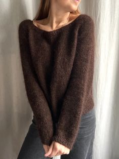 a woman is wearing a brown sweater and jeans