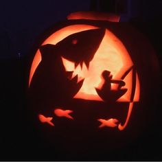 a carved pumpkin with an image of a shark and cat on it's face